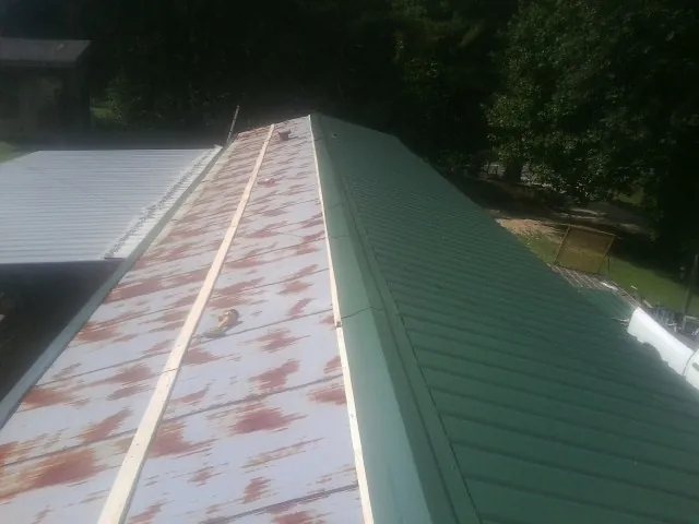 Old rusted panels beside newly installed green metal roofing — Wind Damage Roof Repair by Roofing Brothers in Hinsdale