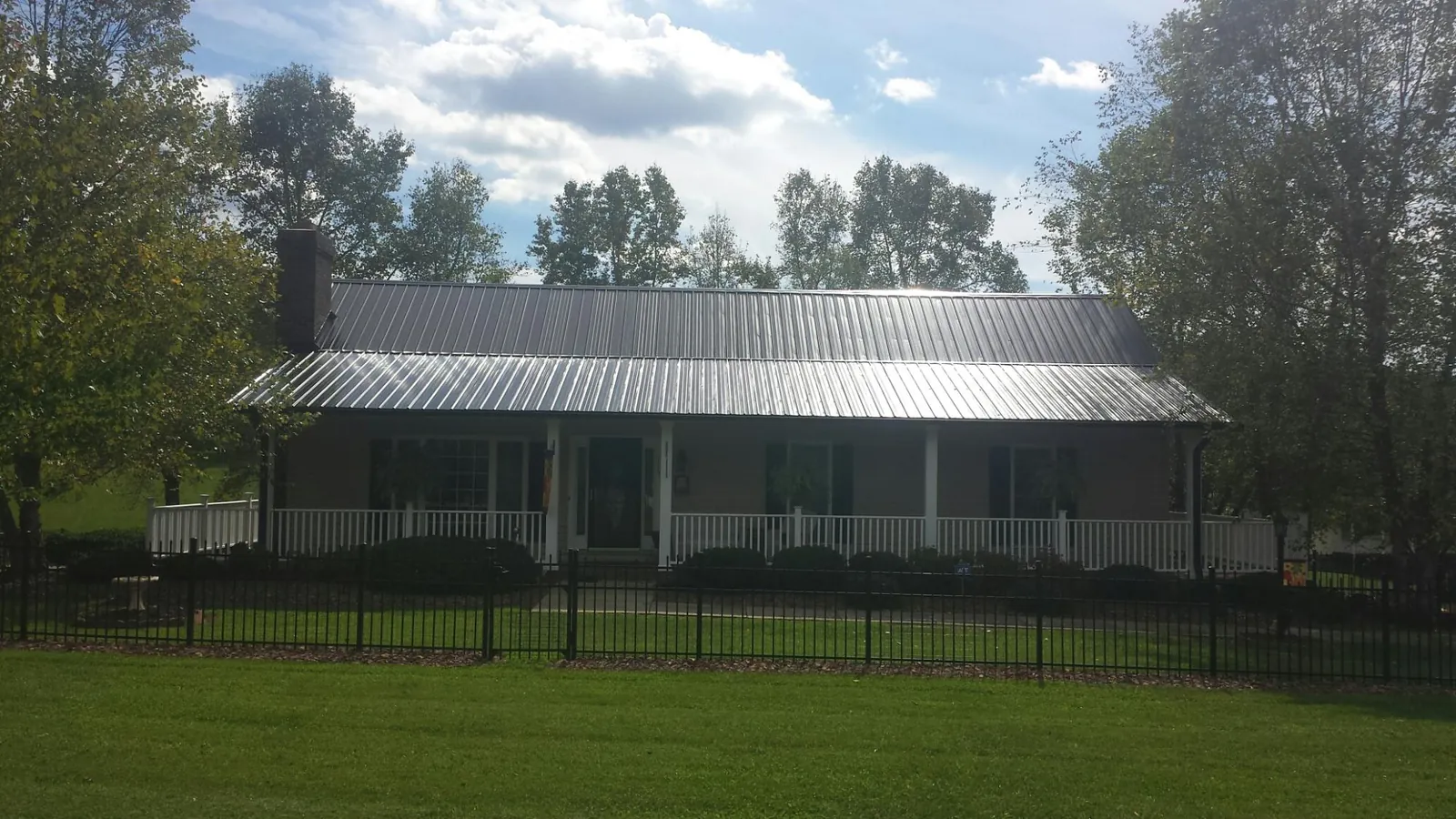 Gray metal roof on a brick ranch with a full width front porch — Gutter Guard Installation work by our crew in Hinsdale